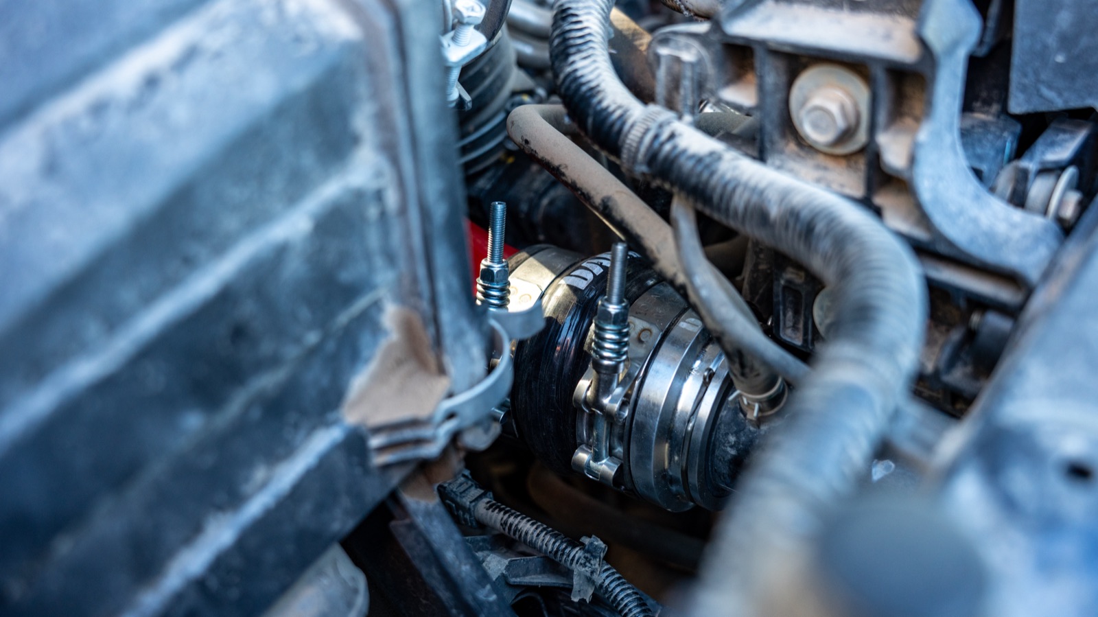 Banks billet quick-connect adapter clamped to the stainless charge tube at the charge-air connection in the 4G Tacoma engine bay, with a constant-tension clamp and a plugged factory sensor-port bung visible