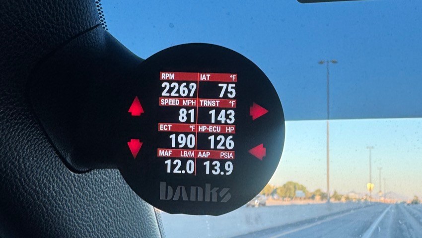 Banks iDash mounted on the A-pillar of a 4G Tacoma, live on an Arizona highway at 81 mph, reading 2269 RPM, transmission temp 143F, coolant 190F, 126 HP at the ECU, mass airflow 12.0, and 13.9 psia manifold pressure
