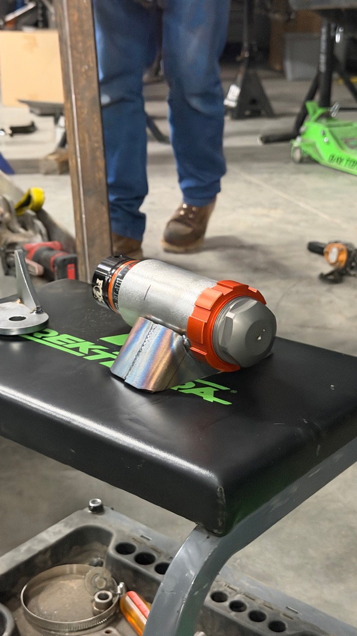 FOX hydraulic bump stop and orange locking ring resting in a fabricated metal mounting assembly on a shop seat