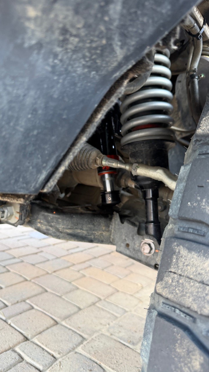 View behind the installed front tire showing the FOX hydraulic bump stop beside the coilover and steering linkage