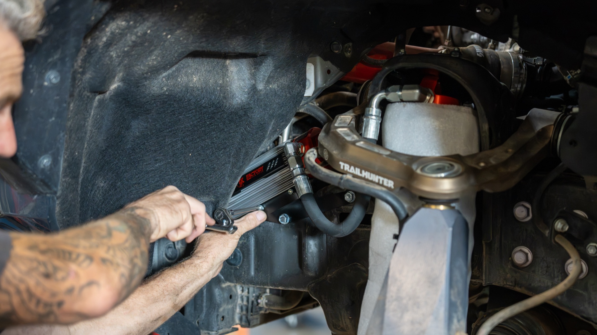 SDHQ tech fastening the front Live Valve reservoir behind the fender liner of my Tacoma, Trailhunter upper control arm in frame — photo: SDHQ Off Road