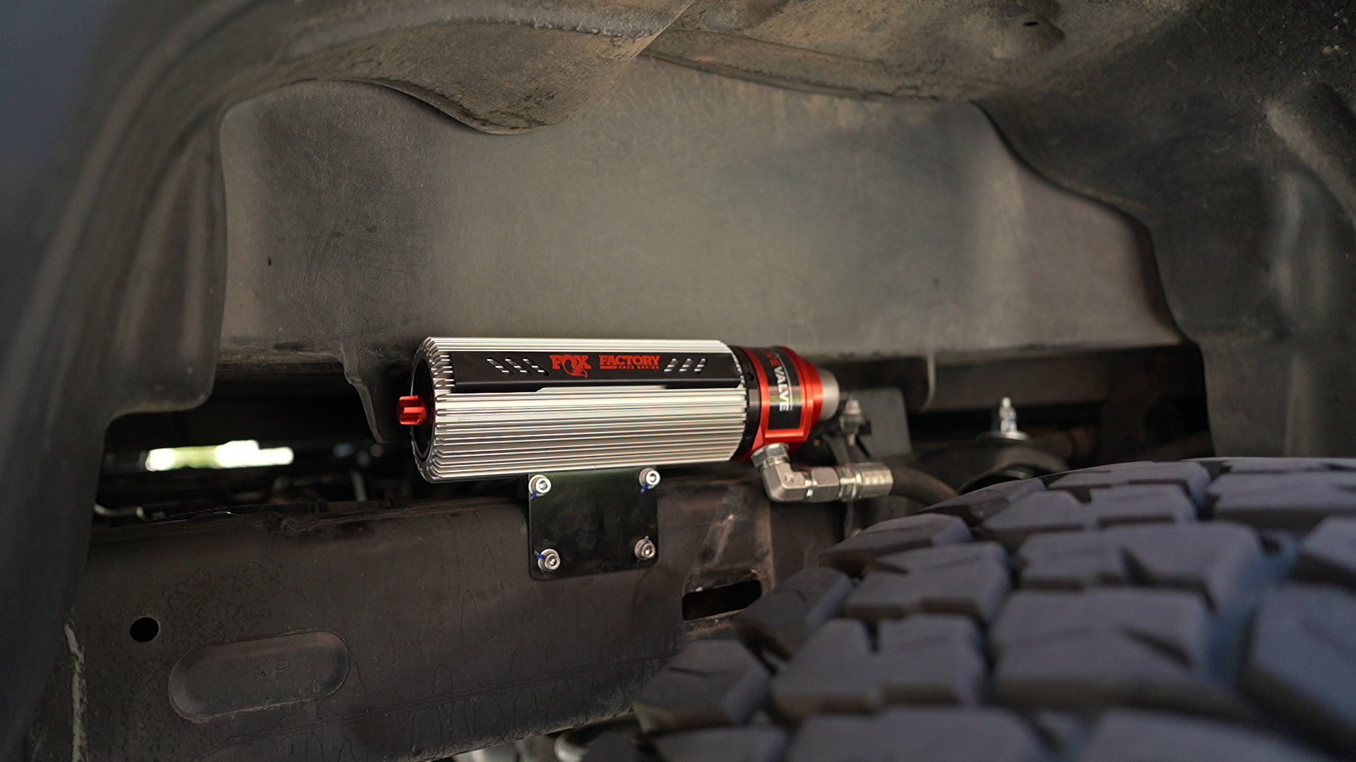 Fox Factory reservoir and red Live Valve solenoid clamped to the frame rail bracket on my Tacoma, 37-inch Toyo tread just below — photo: SDHQ Off Road