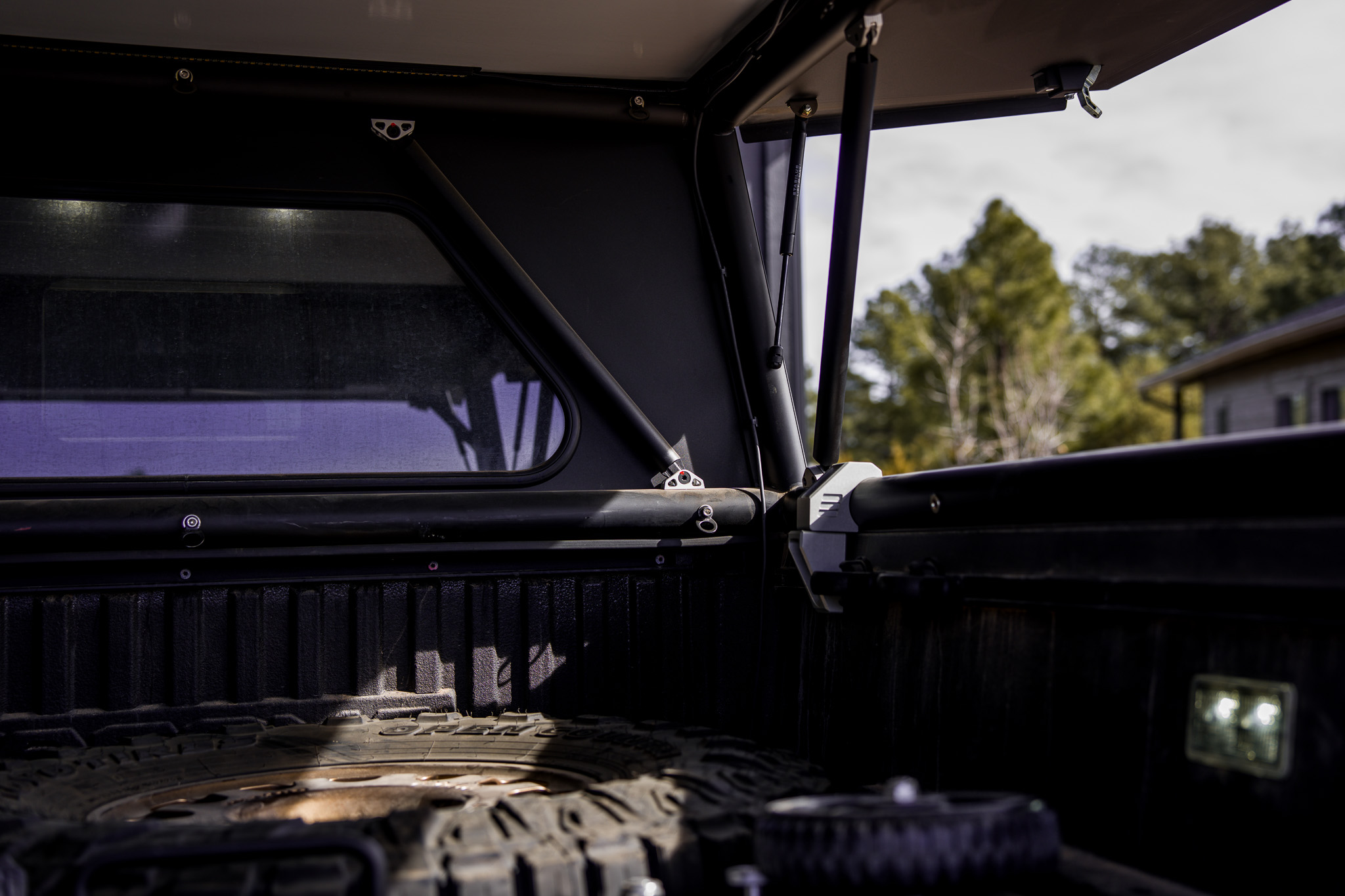 GFC bed area showing spare tire, gas struts, and bed light