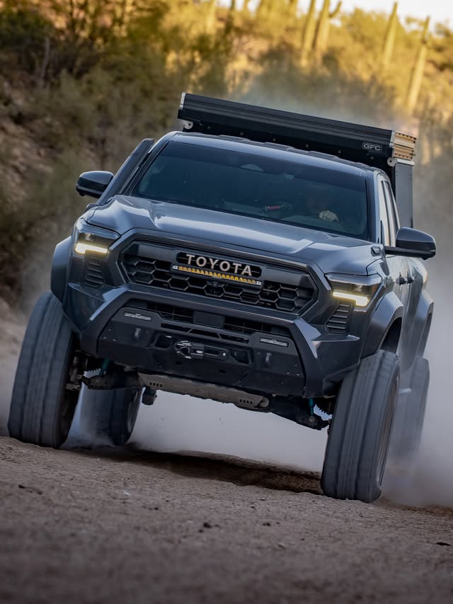 Tacoma on 37s climbing a dirt berm at a low front three-quarter angle