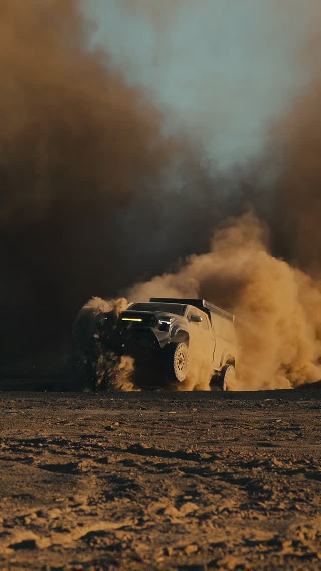 Tacoma with rooftop camper throwing a dust cloud off-road