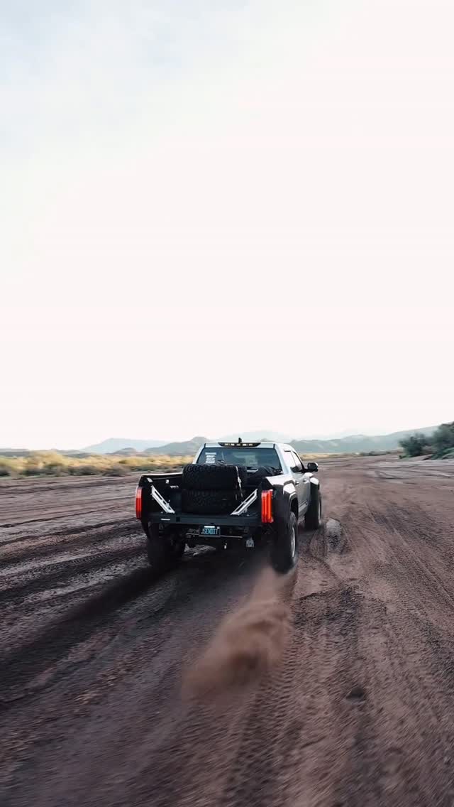 Tacoma blasting through dirt trail with dust plume